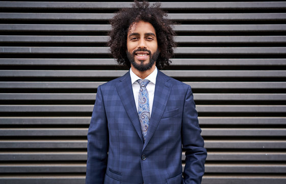 Presentable black man standing near striped wall