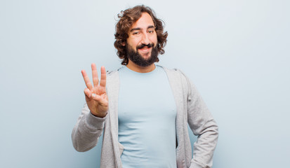 young bearded crazy man smiling and looking friendly, showing number three or third with hand...