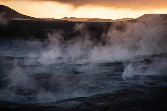 Geyser and volcanic lands at sunrise. Geothermal industry.