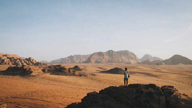 Woman stands on top of the rock looking at Wadi Rum