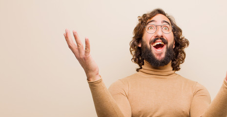young bearded crazy man feeling happy, amazed, lucky and surprised, celebrating victory with both...