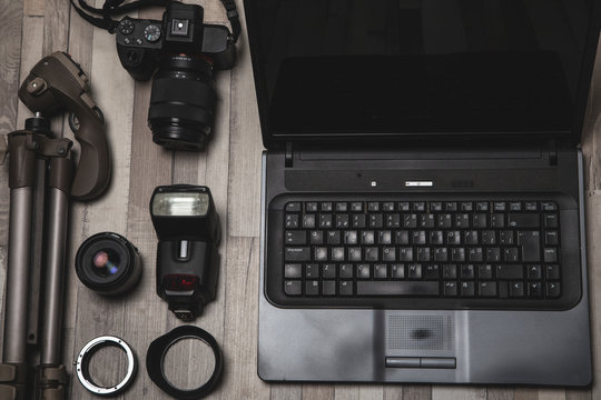 From above set of professional photography equipment arranged near laptop on wooden surface