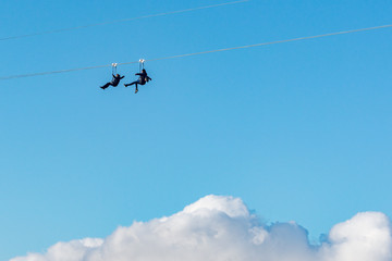 Man and woman move above the clouds on the mountain attraction. Sochi. Russia.
