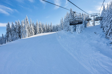 Ski area in sunny moutain. Chair ski lift over slope for ski and snowboard. Sports and recreation concept. Selective focus.