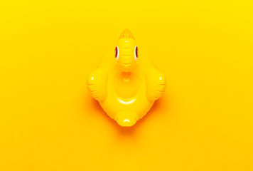 Creative summer beach concept. Inflatable mini yellow chicken or duckling on yellow background, pool float party. Flat lay copy space. Trend Inflatable Children toy for swimming. Layout for design