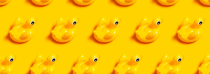 Creative summer beach concept. Seamless Pattern of Inflatable mini yellow chicken or duckling on yellow background, pool float party. Flat lay copy space. Trend Inflatable Children toy for swimming