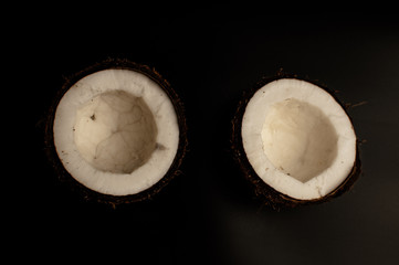 ugly organic coconut on a black background, isolate. a broken nut in a shell the white insides of a...