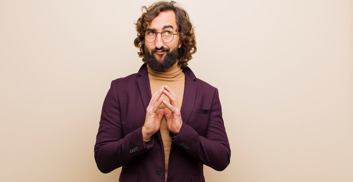 young bearded crazy man scheming and conspiring, thinking devious tricks and cheats, cunning and betraying against flat color wall