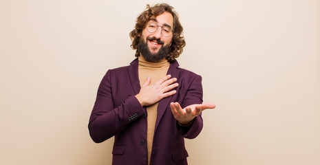 young bearded crazy man feeling happy and in love, smiling with one hand next to heart and the...