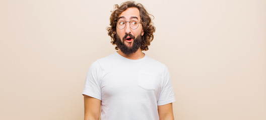 young bearded crazy man feeling shocked, happy, amazed and surprised, looking to the side with open...