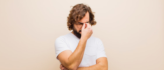 young bearded crazy man feeling stressed, unhappy and frustrated, touching forehead and suffering...