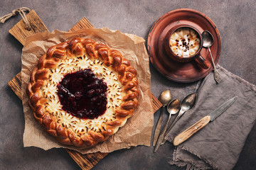 Pie with cottage cheese with strawberry jam, a cup of hot coffee, rustic dark background. Top view, flat lay.