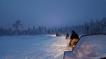Snowmobiling in Rovaniemi behind the Arctic circle. Finland. Snowmobile safari during the midnight sun in finnish Lapland. 