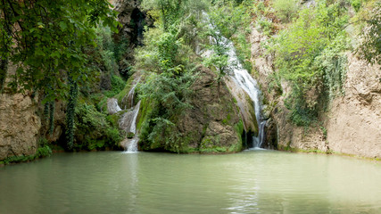 View with a waterfall and a lake surrounded by greenery