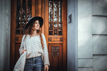Young fashionable woman standing in old stylish door of building