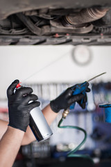 Car master mechanic repairer lubricates screws with machine cleaner spray