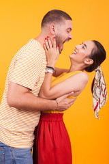 Cheerful young couple in studio over yellow background