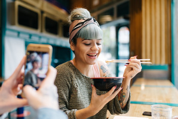 Man taking photo of laughing womanÂ in cafe