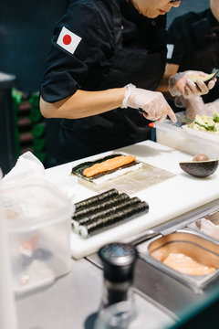 Asian woman making sushi at table