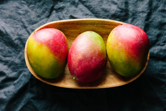 Three mango fruit in a mango wood platter