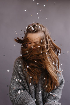 Unrecognizable woman with long swirling hair under the rain of confetti