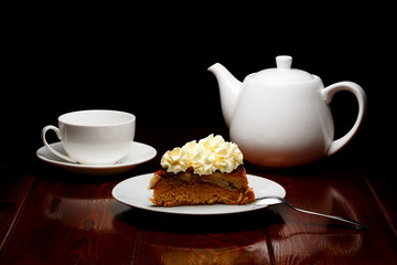 White tea cup and teapot with a slice of apple pie on a dark background from brown lacquered wooden boards. A logo can be conveniently placed on a cup and teapot.