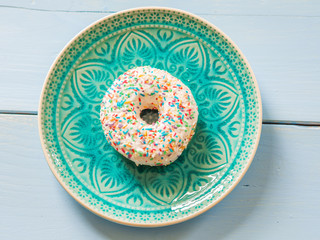 Delicious sprinkled white sweet donut - top view