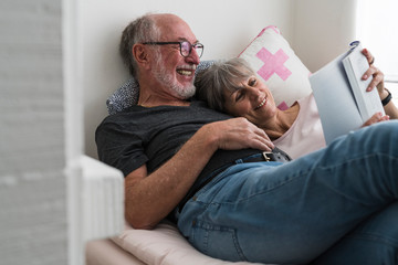 Elderly couple reading a book at home