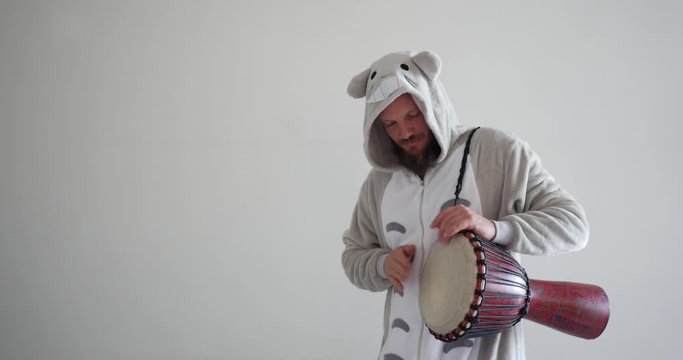 handsome musician drumming on djembe, African drum with his hands, dressed up as an animal for musical art education class. Professional UHD medium shot of crazy funny teacher.