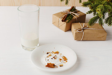 Empty glass of milk and crumb biscuits and a gift under the Christmas tree. The concept of the arrival of Santa Claus.