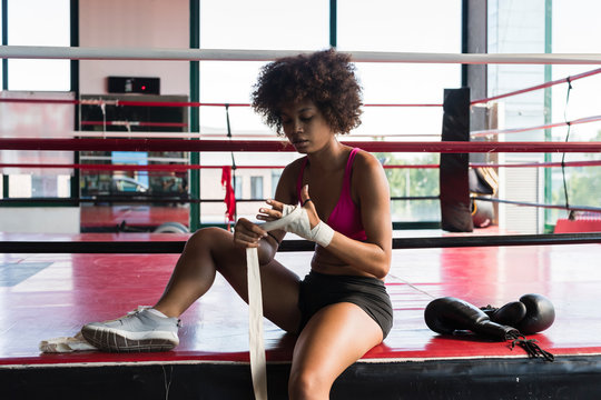 Black woman wrapping her hands preparing to boxe