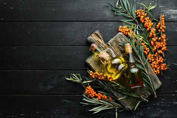 Sea buckthorn oil. Fresh sea buckthorn berries on a twig. Top view. Free space for your text.