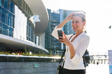 Blonde businesswoman using a phone in the city