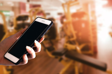 hand of sport girl holding device smartphone application trainer in fitness gym background by body exercise workout for healthy concept