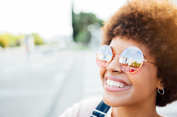 Portrait of a happy beautiful black woman with sunglasses at the street