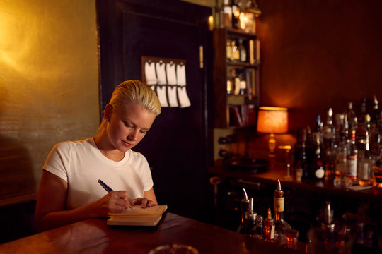 A bartender writing on her notebook. - Powered by Adobe
