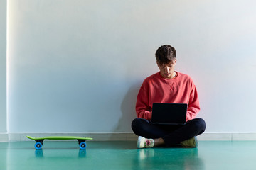 Teenage boy sitting on the floor with his laptop