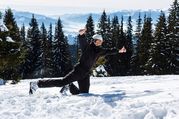 A skier or snowboarder stands on a hill or a slope on a background of mountains covered with...