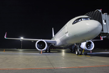 A white passenger jet plane stands at the air bridge connected to an external power supply on an...