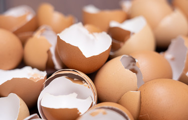 Close up of broken organic raw chicken eggs shell on brown wooden floor background