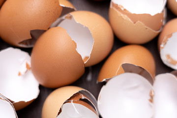 Close up of broken organic raw chicken eggs shell on brown wooden floor background