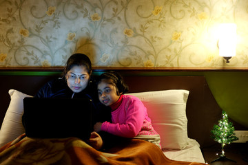 Little girl and her mother busy with laptop