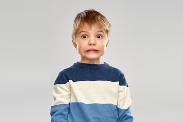 childhood, expressions and people concept - shocked little boy in striped pullover over grey...