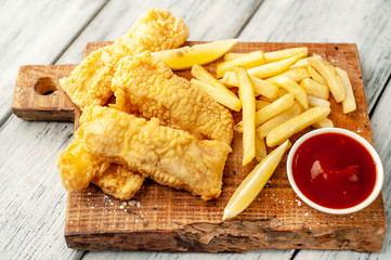 Naklejka premium fish and chips with french fries, on wooden background