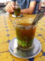Moroccan tea with mint, on table with yellow and blue tiles. Marrakech, Morocco