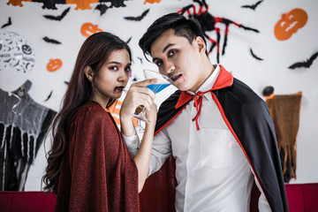 Couple in costume witch and dracula with celebrate Halloween party and drink wine together.
