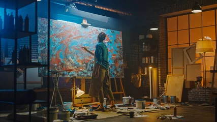 Fotobehang Schilderij Talented Female Artist Works on Abstract Oil Painting, Using Paint Brush She Creates Modern Masterpiece. Dark and Messy Creative Studio where Large Canvas Stands on Easel Illuminated.  © Gorodenkoff
