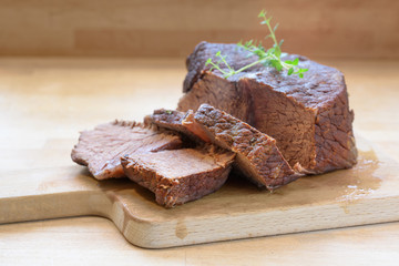 Slices of roast beef, ready braised in red wine with thyme garnish on a wooden table for a festive dinner like boeuf bourguignon, copy space