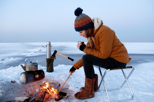 Young woman with mug near campfire