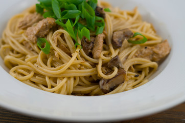 Creamy spaghetti with chicken and mixed mushrooms. Sprinkled with spring onions cut into rings. Freshly prepared and served as a healthy and fast meal of Italian cuisine.